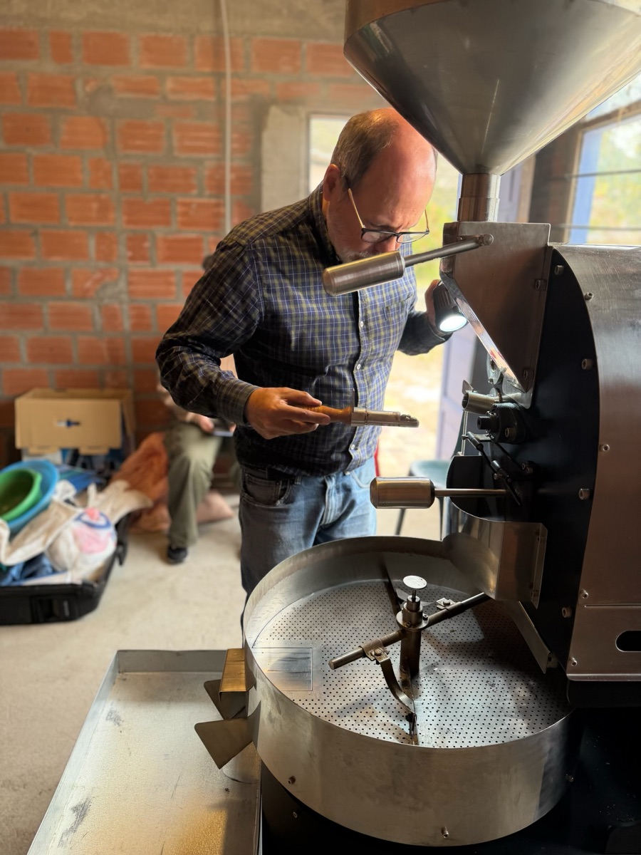 Checking the drum roaster mid-roast in a brick-walled roastery