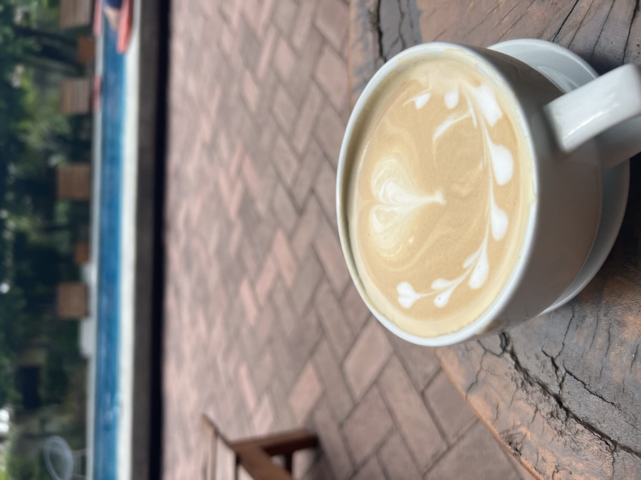 Latte with latte art on a wooden table beside a pool