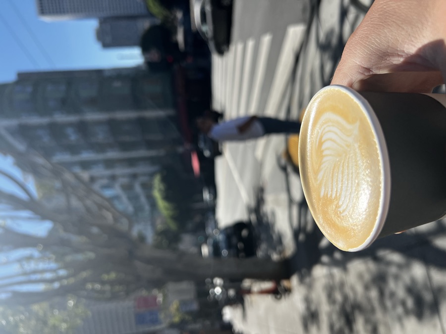 Holding a paper cup of latte on a sunny city street