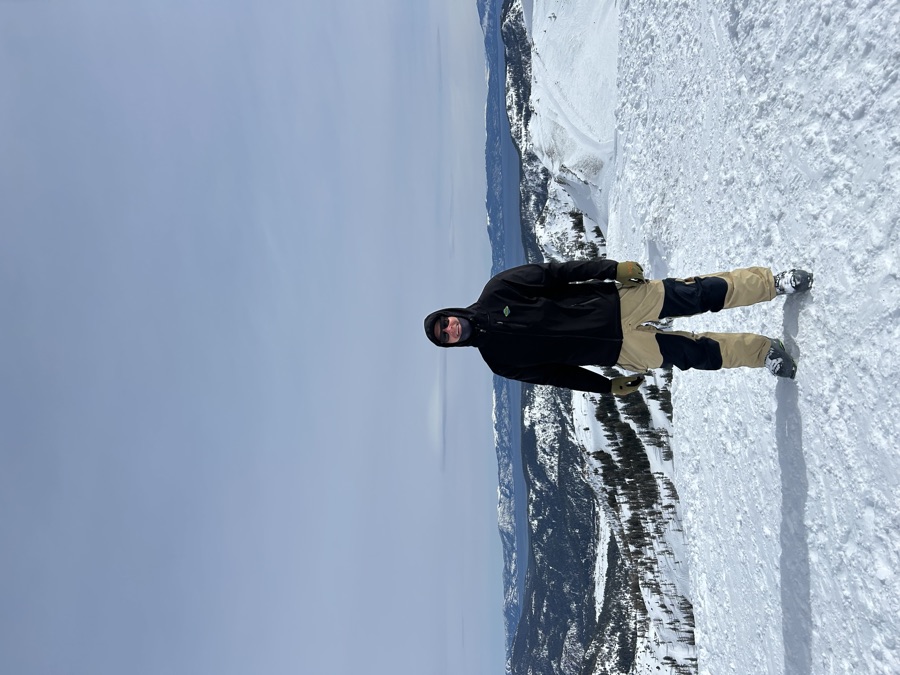Standing on a snowy summit with Lake Tahoe and the surrounding peaks in the distance