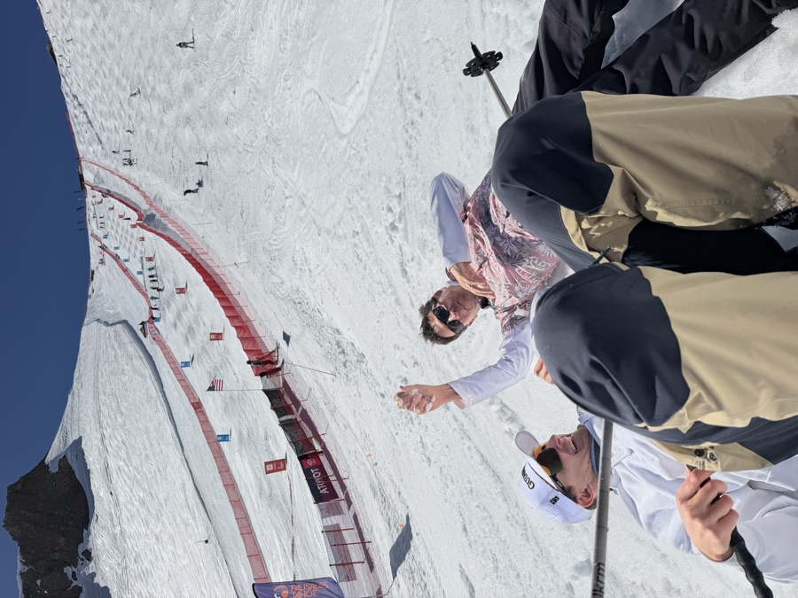 Two skiers high-fiving in the snow below a spring slalom race course