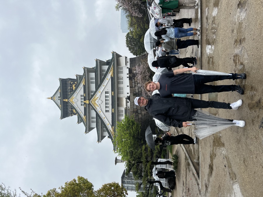 Holding umbrellas in front of Osaka Castle in the rain